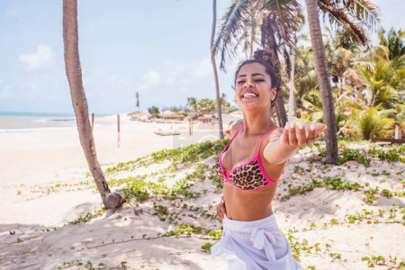 Foto de Hermosa mujer afro de vacaciones en la playa. Mujer afro extendiendo la mano para la invitación de viaje - Imagen libre de derechos