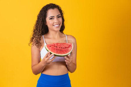 Photo for Beautiful young afro woman posing with watermelon on yellow background. - Royalty Free Image