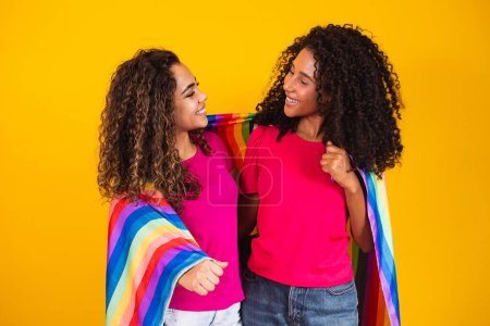 Téléchargez les photos : Couple lesbienne femme avec gay pride drapeau en jaune fond - en image libre de droit