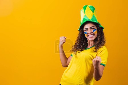 Photo for Brazilian supporter. Brazilian woman fan celebrating on soccer or football match on yellow background. Brazil colors. Yes! - Royalty Free Image
