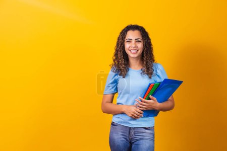 Photo for Young African American teenage student in casual clothes holding books isolated on yellow background studio portrait. Education at high school university college concept. mock up copy space - Royalty Free Image
