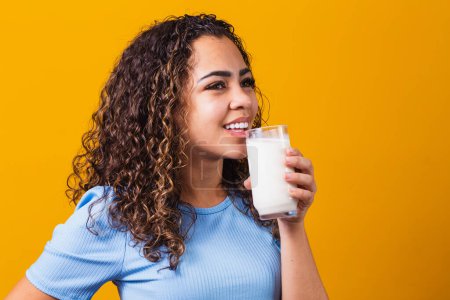 Téléchargez les photos : Jeune fille boire un verre de lait sur fond avec de l'espace pour le texte. - en image libre de droit