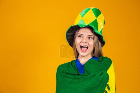 Photo for Blonde brazilian fan celebrating on yellow background with brazil flag - Royalty Free Image