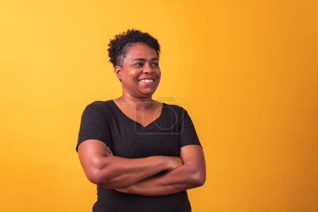 Téléchargez les photos : Femme afro mature avec des bras croisés en arrière-plan jaune - en image libre de droit