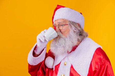 Téléchargez les photos : Real Santa prendre un café sur fond jaune avec espace libre pour le texte. - en image libre de droit