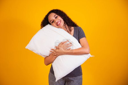 Foto de Foto de una chica afro de ensueño abrazando la almohada somnolienta sobre fondo amarillo con espacio libre para el texto. - Imagen libre de derechos