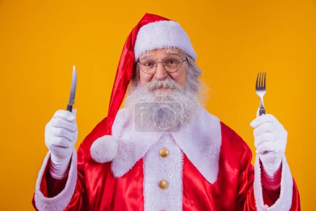 Photo for Santa Claus holding a knife and fork - Royalty Free Image