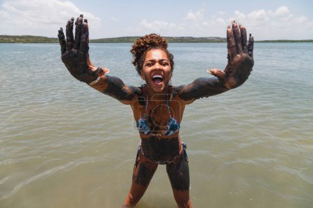 Photo for Young afro woman bathing in natural clay in the river. - Royalty Free Image