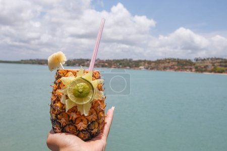 Photo for Hands holding pineapple drink with beach background. - Royalty Free Image