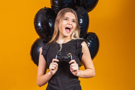 Photo for Promotion of black friday in electronics. Young girl holding a video game controller on yellow background. Young man playing video game concept - Royalty Free Image