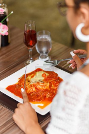 Téléchargez les photos : Femme manger un délicieux plat de viande et nouilles parmigiana. - en image libre de droit