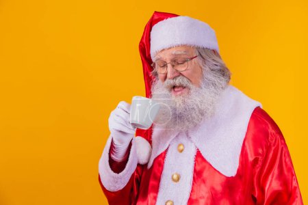 Foto de Real Santa tomando un café sobre fondo amarillo con espacio libre para texto. - Imagen libre de derechos