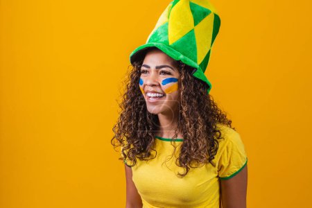 Téléchargez les photos : Un partisan brésilien. Fan de femme brésilienne célébrant sur le football ou match de football sur fond jaune avec espace de copie. Couleurs Brésil. - en image libre de droit