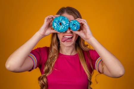 Photo for Portrait of a cheery pretty girl holding blue donuts at her face - Royalty Free Image