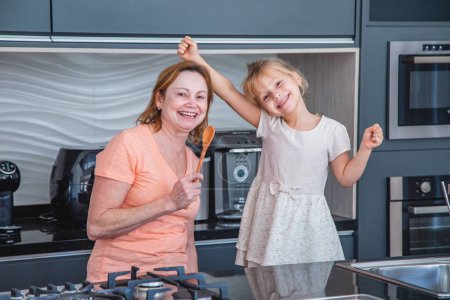 Téléchargez les photos : Bonne fête des mères ! Enfant fille et maman cuisiner et s'amuser dans la cuisine à la maison. Vacances en famille et convivialité
. - en image libre de droit