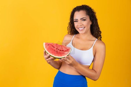 Photo for Beautiful young afro woman posing with watermelon on yellow background - Royalty Free Image