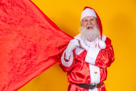 Foto de Santa Claus sobre fondo amarillo sosteniendo bolsa de regalo. - Imagen libre de derechos