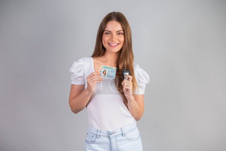 Téléchargez les photos : Femme brésilienne blonde titulaire d'un permis de conduire et d'une clé de voiture. Traduction en anglais (permis de conduire national) - en image libre de droit