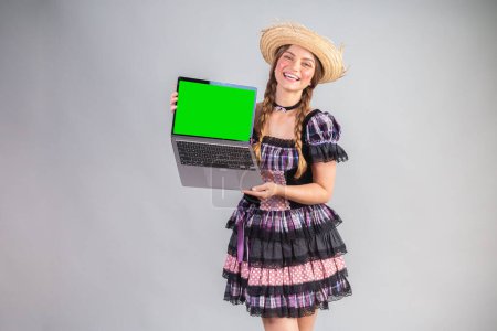 Photo for Blonde Brazilian woman, June party clothes, arraial. notebook, green screen. - Royalty Free Image