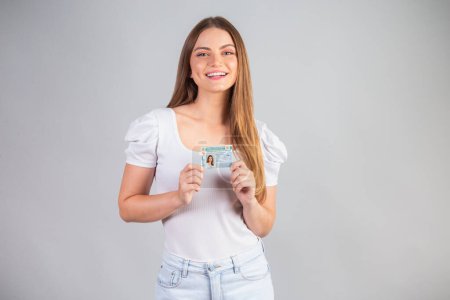 Photo for Blonde Brazilian woman holding a motor vehicle driver's license. Translation in English (national driver's license) - Royalty Free Image