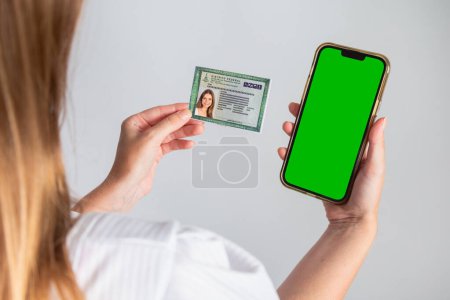 Téléchargez les photos : Femme brésilienne blonde tenant RG, carte d'identité et smartphone. Traduction en anglais (carte d'identité nationale)) - en image libre de droit