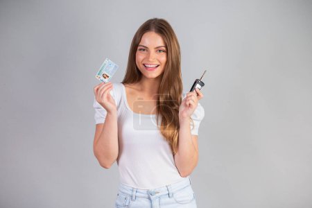 Photo for Blonde Brazilian woman holding motor vehicle driver's license and car key. Translation in English (national driver's license) - Royalty Free Image