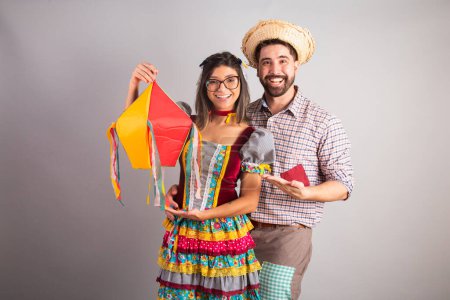 Photo for Brazilian couple dressed in festa junina clothes, feast of So Joo holding arraial decoration. - Royalty Free Image