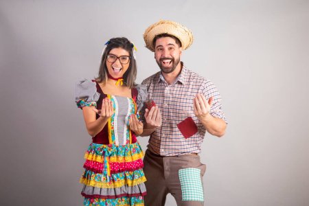 Téléchargez les photos : Couple brésilien vêtu de vêtements de fête junina, fête de So Joo invitant avec les mains, venez ici. - en image libre de droit