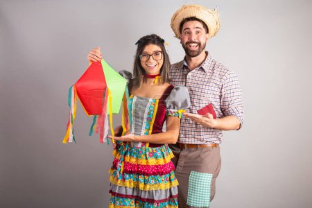 Photo for Brazilian couple dressed in festa junina clothes, feast of So Joo holding arraial decoration. - Royalty Free Image