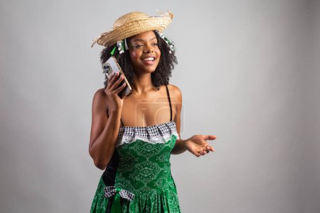 Téléchargez les photos : Portrait, femme brésilienne noire en habits de fête junina. Le festival de Saint John. tenant Smartphone, écran vert. - en image libre de droit