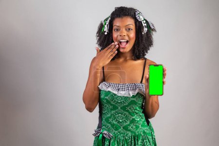 Téléchargez les photos : Portrait, femme brésilienne noire en habits de fête junina. Le festival de Saint John. tenant Smartphone, écran vert. - en image libre de droit