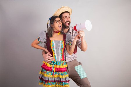 Téléchargez les photos : Couple brésilien vêtu de vêtements de fête junina, fête de So Joo criant avec mégaphone. - en image libre de droit