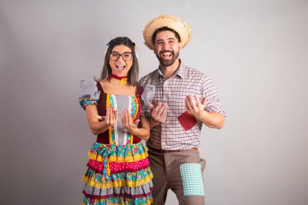 Photo for Brazilian couple dressed in festa junina clothes, feast of So Joo inviting with hands, come here. - Royalty Free Image