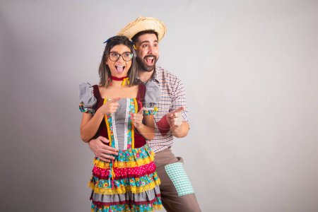 Téléchargez les photos : Couple brésilien vêtu de vêtements de fête junina, fête de So Joo pointant quelque chose au loin. - en image libre de droit