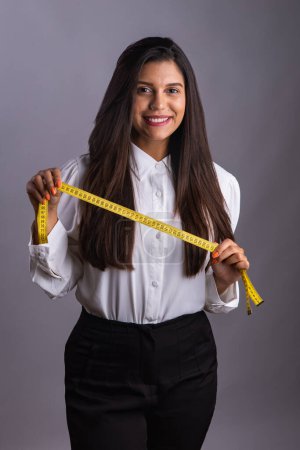 Photo for Brazilian woman, nutritionist, holding measuring tape. Vertical photo. - Royalty Free Image