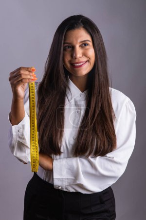 Brazilian woman, nutritionist, holding measuring tape. Vertical photo.
