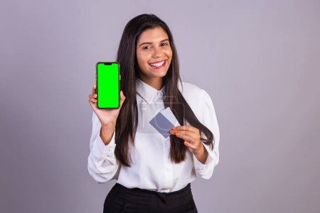 Photo for Brazilian woman holding smartphone, mobile. green screen. and credit cards. - Royalty Free Image