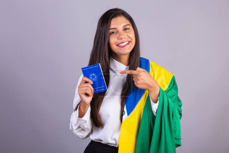 Téléchargez les photos : Femme d'affaires brésilienne, avec drapeau du Brésil et carte de travail. Traduction en anglais (carte d'emploi et sécurité sociale) - en image libre de droit