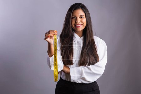Foto de Mujer brasileña, nutricionista, sosteniendo cinta métrica. Fotografía horizontal. - Imagen libre de derechos