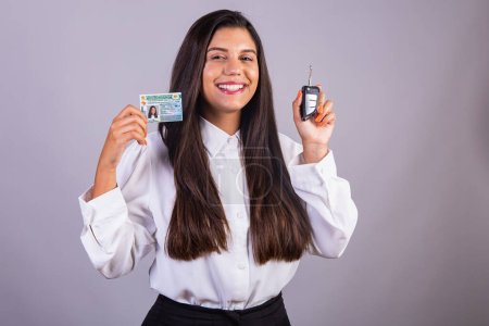 Photo for Brazilian businesswoman with driver's license and car key. Translation in English (national driver's license) - Royalty Free Image