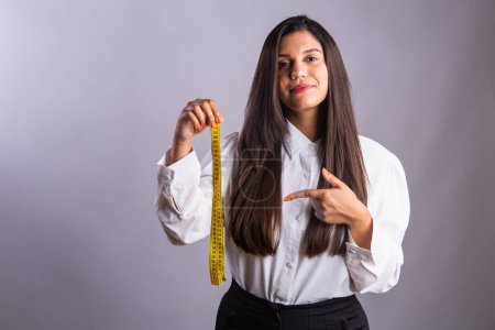 Foto de Mujer brasileña, nutricionista, sosteniendo cinta métrica. Fotografía horizontal. - Imagen libre de derechos