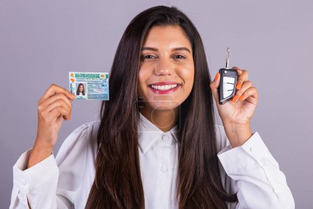 Téléchargez les photos : Femme d'affaires brésilienne avec permis de conduire et clé de voiture. Traduction en anglais (permis de conduire national) - en image libre de droit