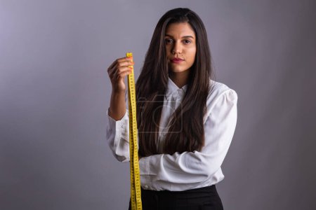 Photo for Brazilian woman, nutritionist, holding measuring tape. Horizontal photo. - Royalty Free Image