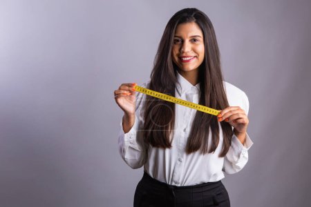 Photo for Brazilian woman, nutritionist, holding measuring tape. Horizontal photo. - Royalty Free Image