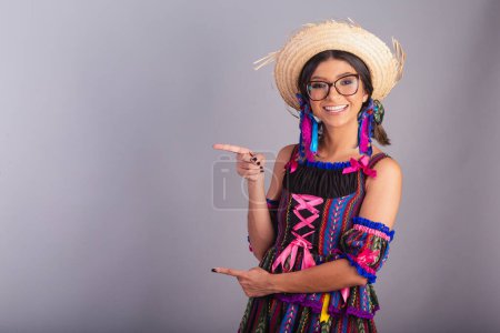 Téléchargez les photos : Femme brésilienne avec des vêtements de festa junina. montrant le produit, la publicité sur le côté. - en image libre de droit