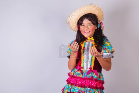Téléchargez les photos : Enfant, fille brésilienne, avec des vêtements Festa Junina, invitant avec les mains. - en image libre de droit