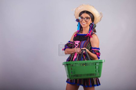 Téléchargez les photos : Femme brésilienne avec des vêtements de festa junina. tenant panier de supermarché. Shopping. - en image libre de droit