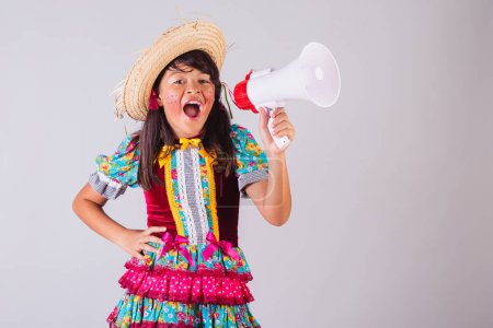 Foto de Niño, chica brasileña, en ropa de fiesta junina, sosteniendo megáfono, anunciando. - Imagen libre de derechos