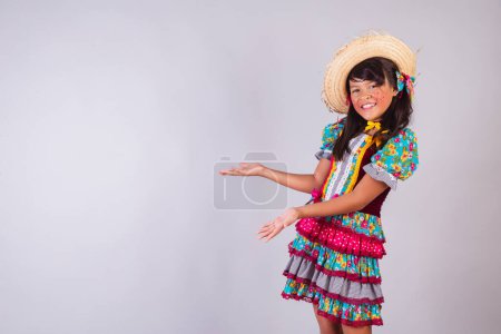 Téléchargez les photos : Enfant, fille brésilienne, avec des vêtements de fête de juin, présentant quelque chose sur le côté, produit, publicité. - en image libre de droit