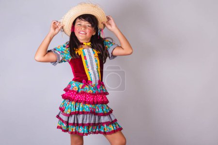 Téléchargez les photos : Enfant, fille brésilienne, dans les vêtements de la fête junina, danse avec la main sur le chapeau. - en image libre de droit